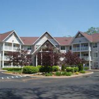 A multi-story residential building surrounded by trees and landscaped greenery.