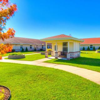 A charming cottage surrounded by a well-maintained lawn and garden on a sunny day.