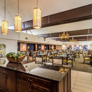 A spacious restaurant interior featuring elegant chandeliers and neatly arranged dining tables.