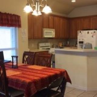 A cozy kitchen and dining area with a table set for a meal, featuring wooden cabinets and modern appliances.