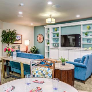 A cozy living room with blue sofas, a television on built-in shelves, and vibrant decor.