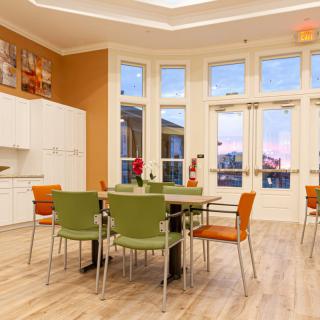 A modern kitchen and dining area with a table, chairs, and large windows.