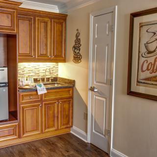 A cozy kitchen nook featuring wooden cabinets, a small fridge, and a coffee-themed poster on the wall.