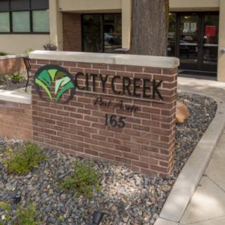 City Creek building entrance sign with landscaped surroundings.