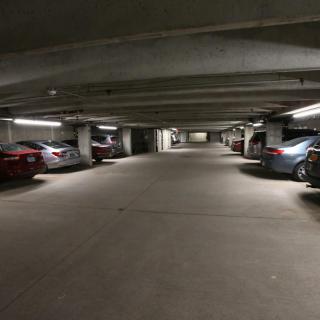 A dimly lit underground parking garage with parked cars.