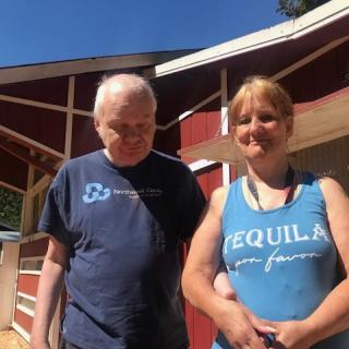 Two people standing outside in front of a red building.