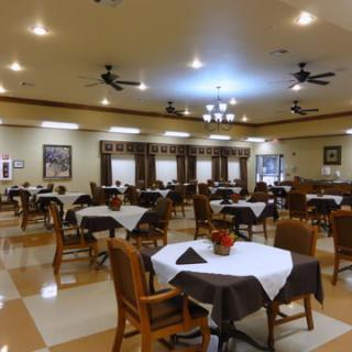 A spacious dining room with neatly arranged tables and chairs, featuring warm lighting and elegant decor.