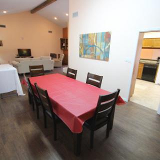 A spacious dining area featuring a large table with a red tablecloth, surrounded by chairs and adorned with modern artwork.