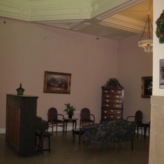 A cozy waiting room featuring chairs, decorative plants, and artwork on the walls.