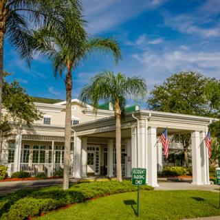 A scenic view of a luxurious hotel entrance surrounded by palm trees and well-maintained landscaping.