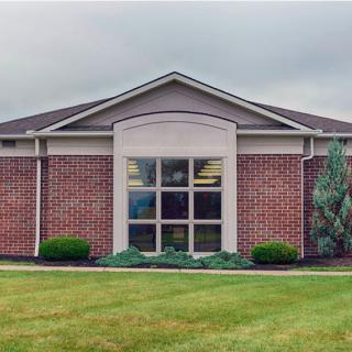 A brick building with large windows and a neatly maintained lawn.
