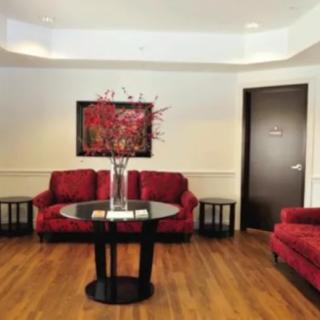 A stylish lobby with red chairs and a central table adorned with a vase.