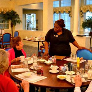 A friendly restaurant scene where a staff member interacts with guests during breakfast.