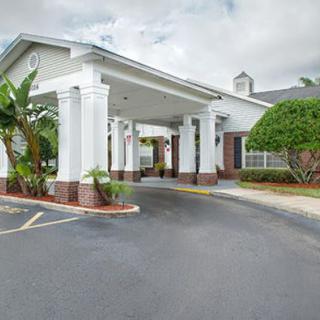 A welcoming entrance to a building with a covered driveway and lush landscaping.