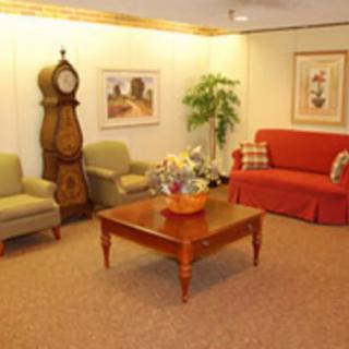 A cozy living room with a mix of seating options, a grandfather clock, and a central wooden coffee table.