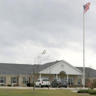 A building with a parking lot and an American flag flying on a cloudy day.