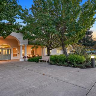 A beautifully landscaped front yard with a spacious driveway leads to a charming house at dusk.