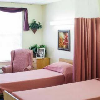 A hospital room with two beds, a privacy curtain, and comfortable seating.