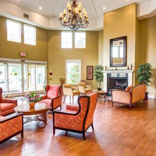 A spacious and elegantly designed living room featuring a chandelier, fireplace, and comfortable seating area.