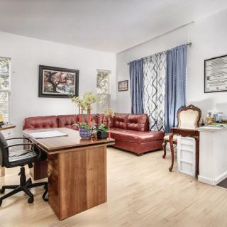A cozy office space with a wooden desk, leather couch, and stylish decor.