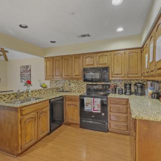 A cozy kitchen with warm wooden cabinets and granite countertops, featuring modern appliances and a stylish tile backsplash.