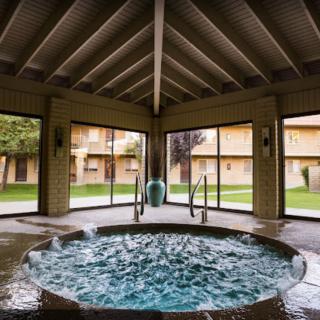 An inviting indoor jacuzzi with large windows overlooking a resort courtyard.