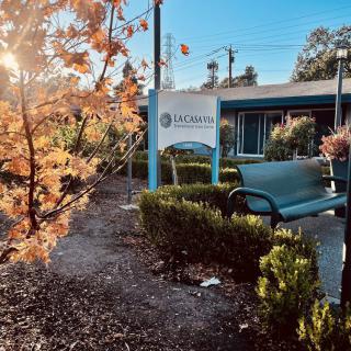 A scenic view of an autumn landscape featuring a building and sign with sunlight filtering through the trees.