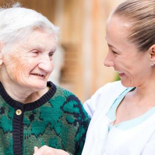 A caregiver smiling and interacting warmly with an elderly woman.