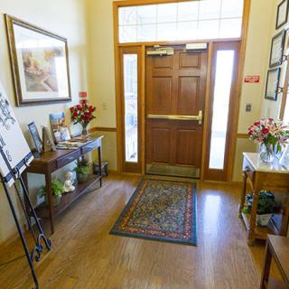 A warmly decorated entrance with wooden doors, a rug, and floral arrangements.
