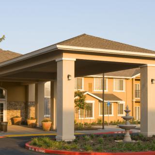 A residential building with a covered entrance and neatly landscaped driveway.