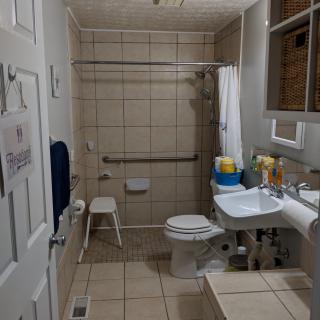 An accessible bathroom with grab bars and a shower chair.