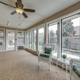 A bright sunroom with large windows, wicker chairs, and a ceiling fan.