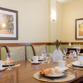A elegantly set dining table with artwork on the walls and a decorative vase centerpiece.