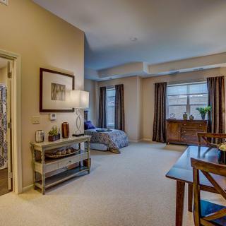 A cozy and well-furnished living room with a carpeted floor, dining table, and large windows.