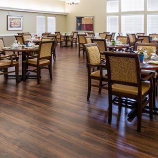 An empty dining room with neatly arranged tables and chairs on a wooden floor.