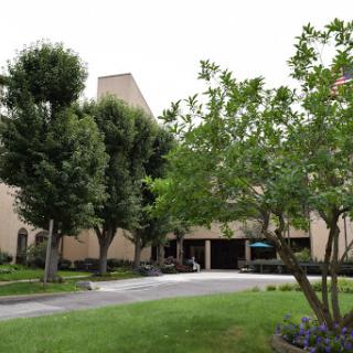 A view of a building surrounded by trees and a manicured lawn.