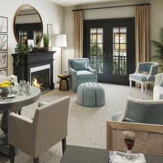 A cozy living room with elegant furnishings, featuring a fireplace and large windows.