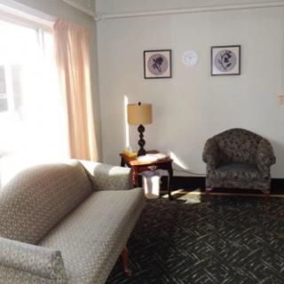A cozy living room with a sofa, armchair, and lamp by the window.