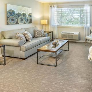 A cozy living room with a sofa, coffee table, and a large window letting in natural light.