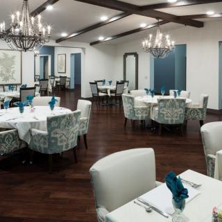 A well-decorated dining room with elegant chandeliers and neatly arranged tables and chairs.