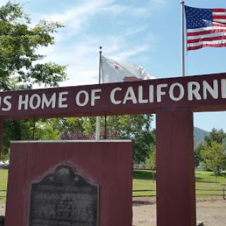 A sign marking a historical site in California, adorned with the American flag.