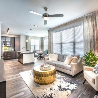A modern open-layout living space with a bright and cozy atmosphere, featuring a comfortable sofa and stylish kitchen.