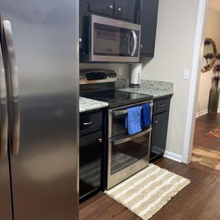 A modern kitchen with stainless steel appliances and a striped rug.
