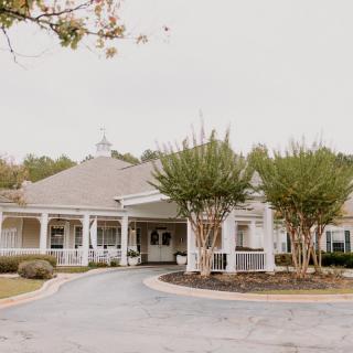 A residential building with a circular driveway and landscaped trees in front.