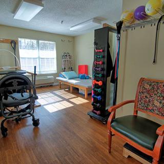 A well-lit physical therapy room equipped with various rehabilitation tools, including a walker and exercise balls.