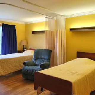 A cozy bedroom featuring two single beds, a comfortable armchair, and bright yellow walls.