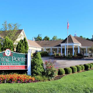 Entrance to a picturesque building surrounded by well-maintained gardens and a prominent sign.