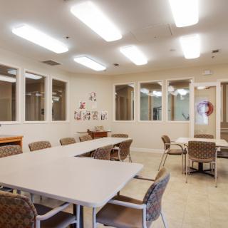 A well-lit meeting room with tables and chairs arranged for a group discussion.