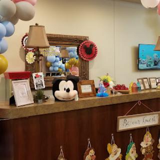 A vibrant reception area decorated with balloons and a Mickey Mouse plush toy, creating a cheerful atmosphere.