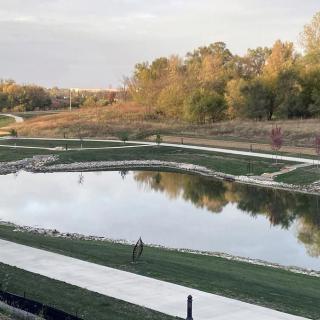A scenic view of a pond surrounded by pathways and trees, reflecting the tranquil natural landscape.